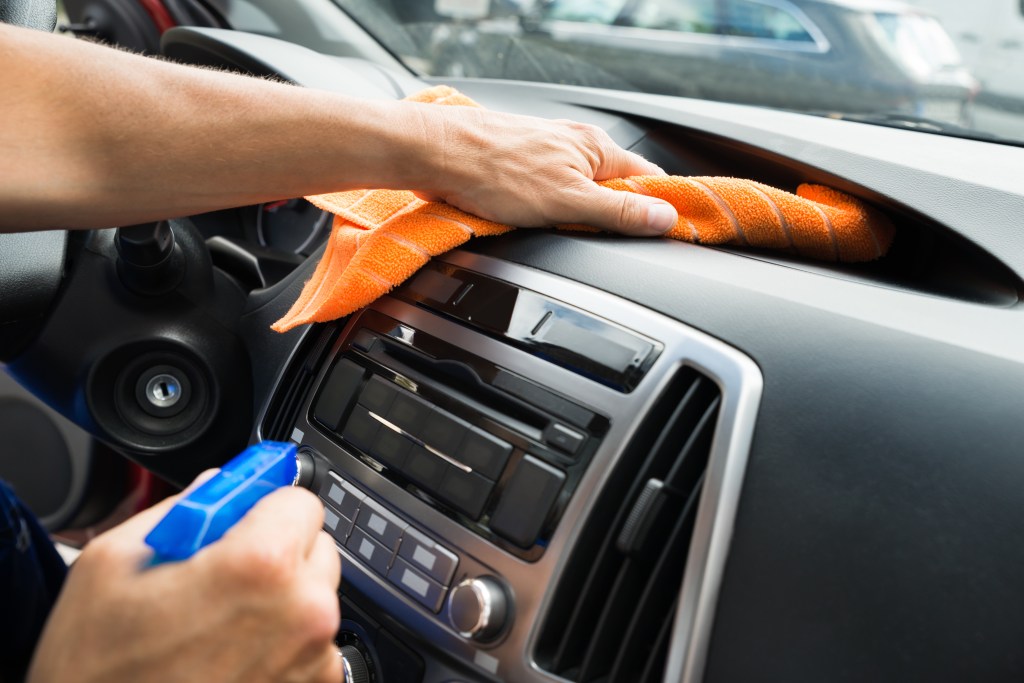 Person wiping down a vehicle dashboard