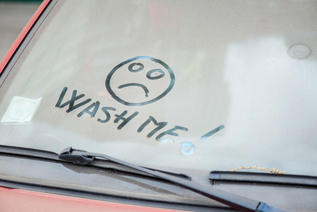 Dirty windshield with Wash Me written in