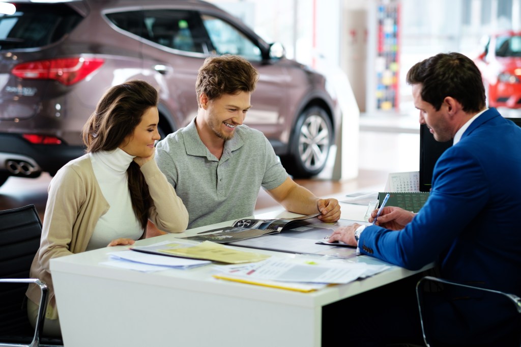 Couple negotiating at car dealership