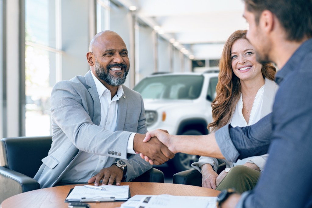 Car buyer shaking hands with dealership representative