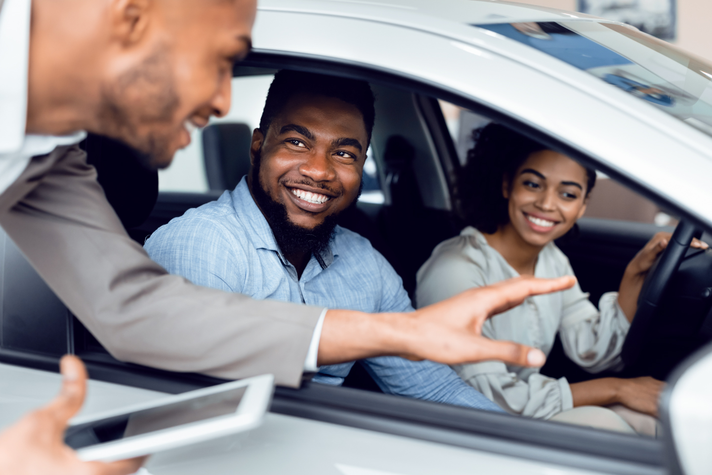 Dealer representative talking to young couple in car