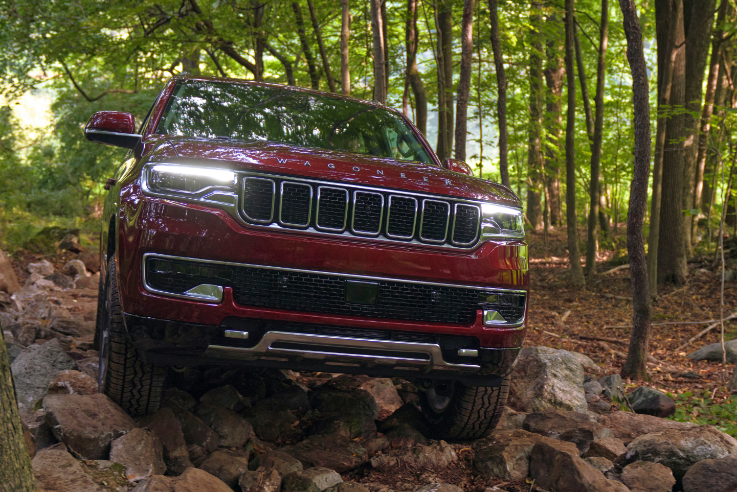 Wagoneer driving over rocks in woodland